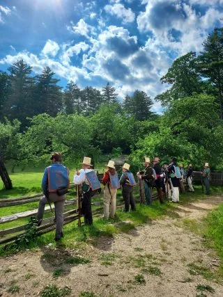 Men in militia uniform lined up by a fence