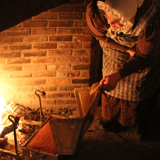 Woman baking near an open hearth.