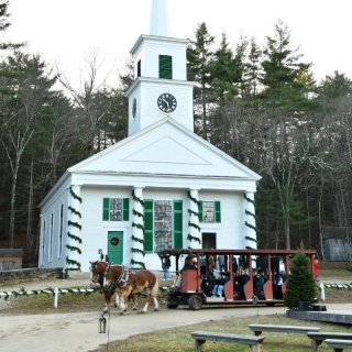 A horse drawn carryall rides by a 19th-century Meetinghouse
