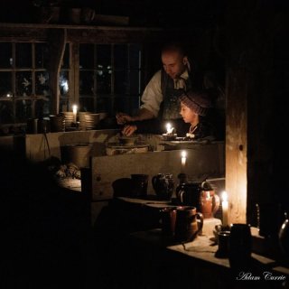 A potter in 19th-century attire helps a child at the potter's wheel