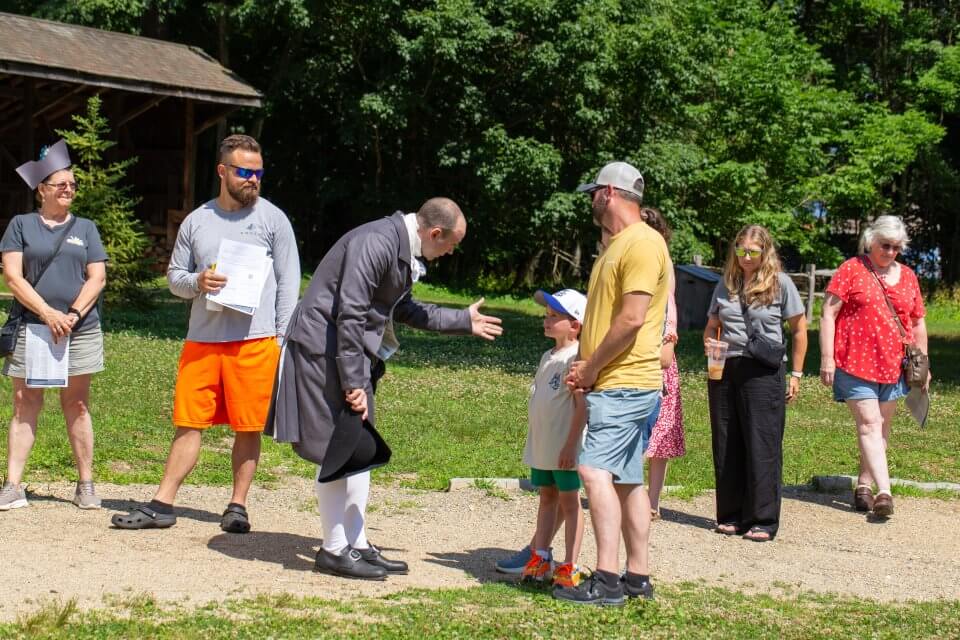 Visitors interact with a man in colonial dress