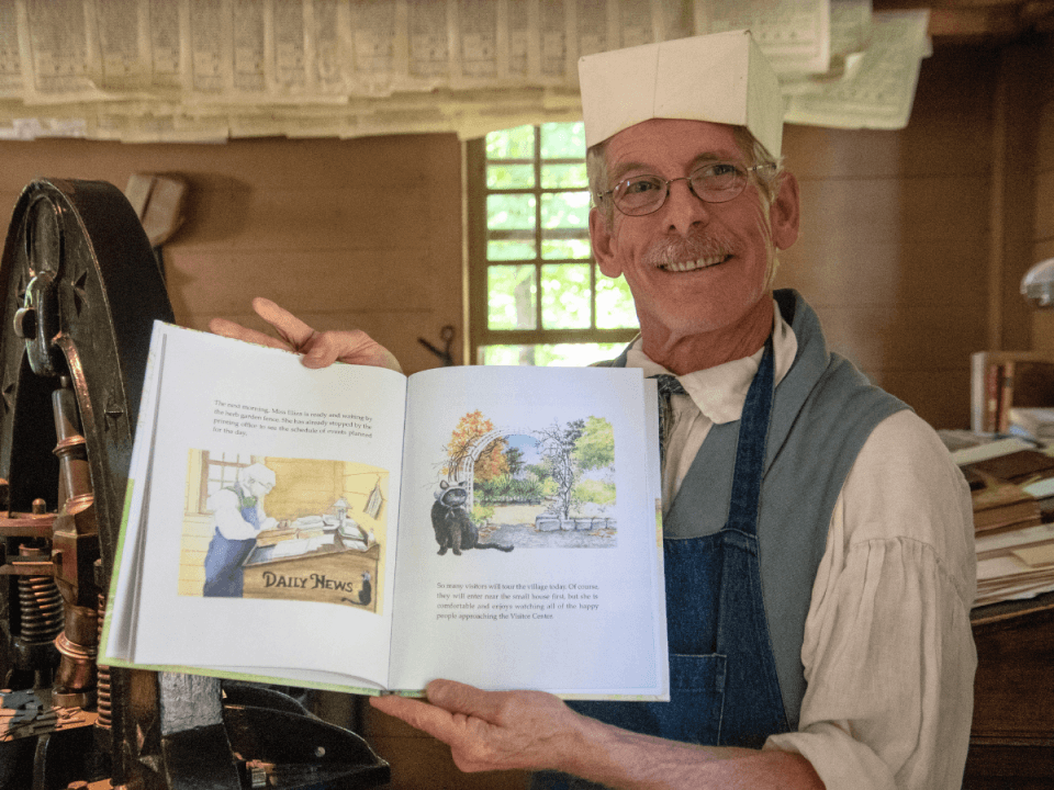 A man in 1830s clothing in a 19th-century printing office holds a cop of Wooly Forgets